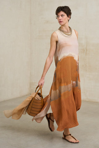 look de mujer con vestido fluido efecto acuarela con estampado en tonos tierra combinado con bolso de piel marrón y sandalias